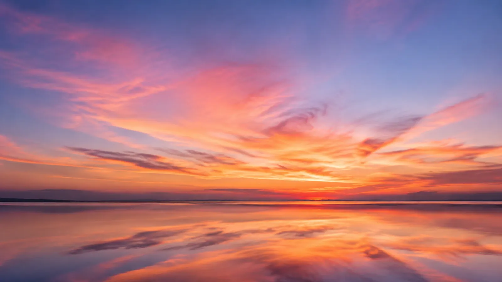 Golden sunset over a quiet beach with gentle waves, footprints, and seashells along the warm sand.